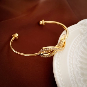 Macro detail of gold-plated knot bracelet with micro-pave white zircon on velvet background