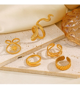Detailed view of five vintage gold snake-shaped and sun motif rings on sandstone