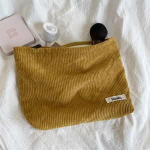 Close-up of yellow corduroy makeup bag texture with brand label on a white background