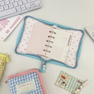 Close-up of quilted sky blue binder and plaid pouch on a minimalist workspace desk