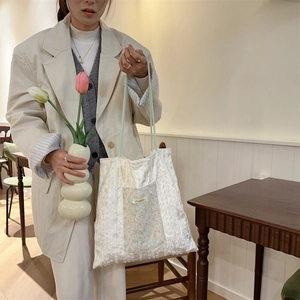 Detailed view of beige lace tote bag featuring intricate embroidery and drawstring design