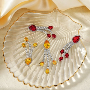 Exquisite copper zircon tassel earrings with pear-cut red and yellow stones in a glass tray