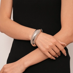 Polished silver chunky geometric open cuff bracelet on female wrist in minimalist style