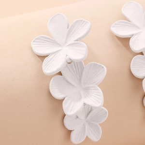 Macro detail of triple white matte floral earrings with delicate petal texture and grain