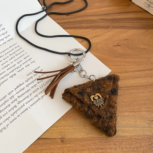 Close-up of brown plush triangle pendant with black beaded chain and tassel on wood surface
