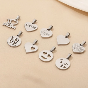 Close-up of polished silver heart pendants with MOM and LOVE engravings on beige fabric