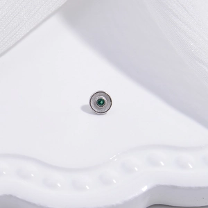 Macro shot of S925 silver round stud earring with a central green gemstone on white fabric