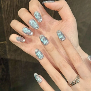 Detailed view of ice-blue cat-eye press-on nails with silver glitter and star ring