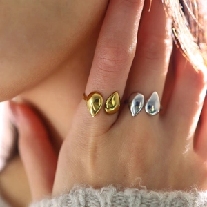 Detail of teardrop shaped 18K gold and silver open rings on fingers with smooth finish