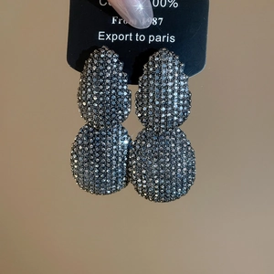 Macro detail of oval drop earrings with grey pavé crystals and vintage layered design