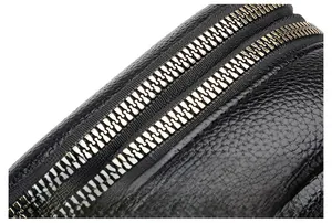 Close-up of dual bronze metal zippers on premium black lychee pattern leather bag