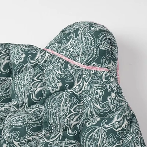 Close-up of green paisley quilted jacket fabric with pink border and thick padding
