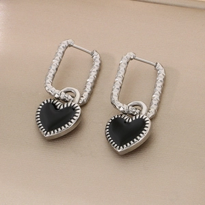 Gros plan sur les boucles d'oreilles cœur en argent avec émail noir et détails texturés