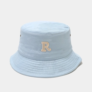 Detail of light blue cotton bucket hat featuring white embroidered letter R and stitched brim