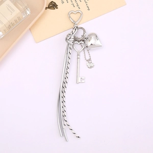 Porte-clés tressé avec breloque cœur argentée et pendentif clé sur fond rose doux