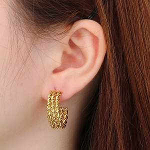 Close-up of golden triple-row braided rope C-shaped earrings worn on a model