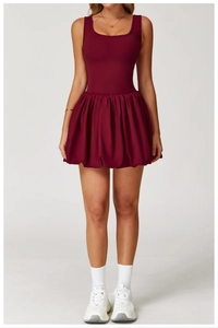 Detail of burgundy tennis dress featuring a sleeveless top and pleated skirt for sports