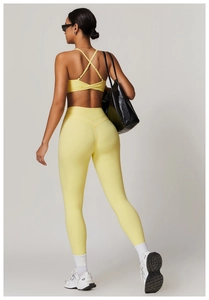 Rear view of light yellow high waisted yoga leggings with cross-back sports bra design