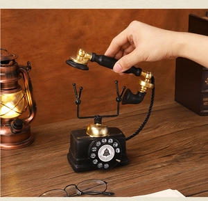 Miniature vintage dial telephone model on a wooden desk with antique books and lamp