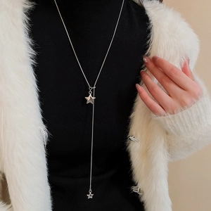 Close-up of a silver Y-shaped necklace with star pendants on a model with white coat