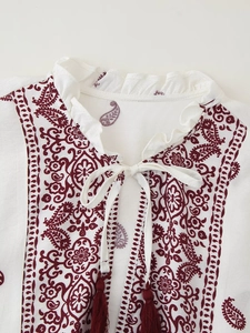 Detail der weißen V-Ausschnitt Bluse mit Paisley-Print, Schnürkragen und Quasten-Details