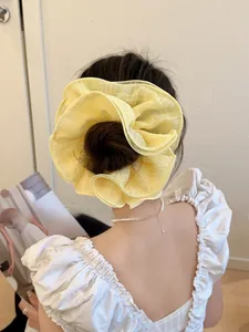 Close-up of a large yellow chiffon layered scrunchie on a classic French bun hairstyle