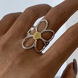 Detailed close-up of hollow flower ring in two-tone silver and gold finish on hand
