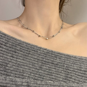 Close-up of double-layer titanium steel necklace with square pendants on grey sweater