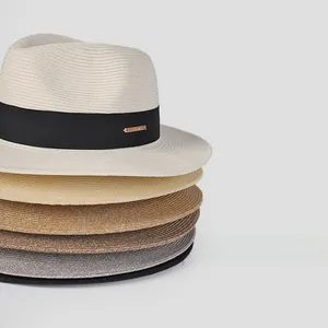 Stacked woven straw boater hats with black ribbons and gold metal buckles in various colors