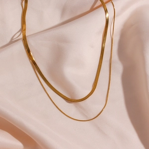 Detail of 18K gold-plated double-layer necklace featuring flat blade and round snake chains