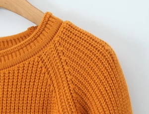 Détail d'un pull orange gingembre à col rond en maille épaisse et texturée robuste