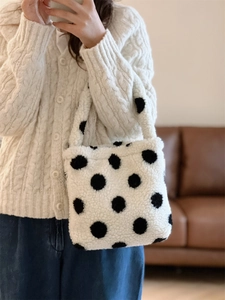 Détail de la texture douce en peluche d'un sac à main blanc à grands pois noirs