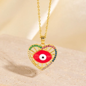 Macro view of gold-plated heart pendant with red enamel Evil Eye and tiny colored gems