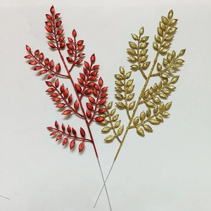 Dettaglio macro di foglie natalizie glitterate con rami scintillanti oro e rosso