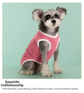 Detail of pink knitted dog vest featuring decorative white pom-poms on premium texture