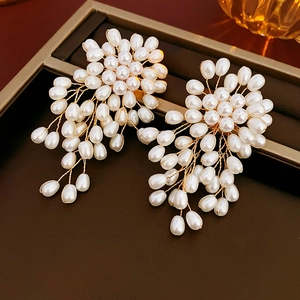 Détail de longues boucles d'oreilles en perles tressées avec tissage en fil doré