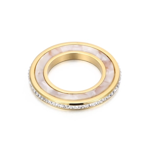 Détail d'une bague dorée avec incrustation en marbre blanc et cristaux sur le côté