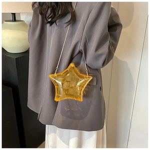 Close-up of a star-shaped transparent amber acrylic crossbody bag with gold chain strap