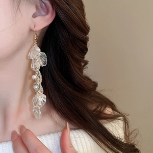 Detailed close-up of iridescent petal tassel earrings with pearls and gold ear hooks