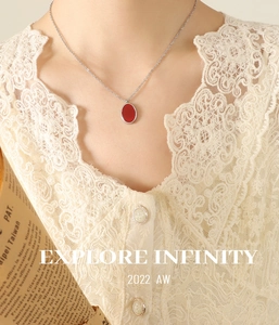 Détail d'un collier argenté avec pendentif ovale rouge porté par un mannequin