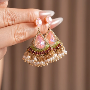 Dettagli di orecchini vintage stile palazzo con gemme rosa e nappe di perle finte