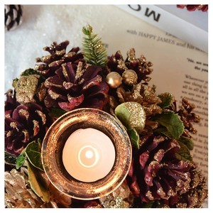 Detail of pine cones, golden leaves and glass candle holder for Christmas decor