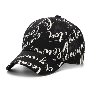 Detail of black baseball cap featuring white cursive script printing and cotton texture