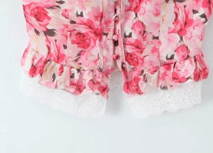 Close-up of floral print with pink roses, white lace trim, and fabric-covered button details