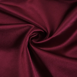 Macro shot of elegant burgundy satin fabric showing smooth texture and glossy silk finish