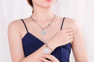 Detail of silver angel coin necklace and bracelet set with pearl charms on a model