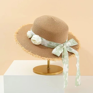 Damen Strohhut mit Blumenband und ausgefranster Krempe auf goldenem Ständer