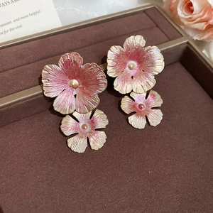Detailed close-up of pink and gold floral gradient earrings with metallic texture detail