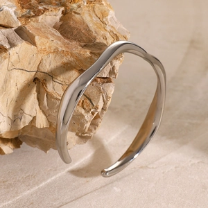 Macro detail of the wave textured silver steel cuff bracelet on a natural stone base