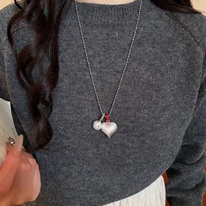 Beaded chain necklace featuring a matte silver heart and black polka dot globe pendant